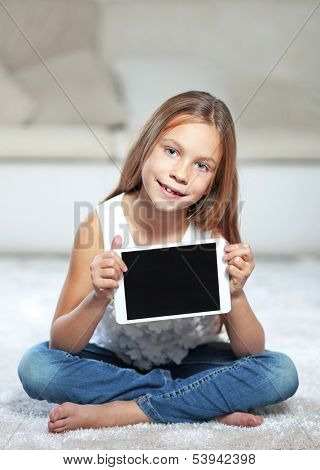 Child playing on tablet pc sitting on a carpet at home