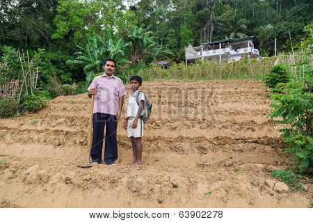 ELLA, SRI LANKA - MARCH 2, 2014: Local farmer and his son stand on tea plantation. Ella is famous for the tea plantations and stunning views across the countryside.