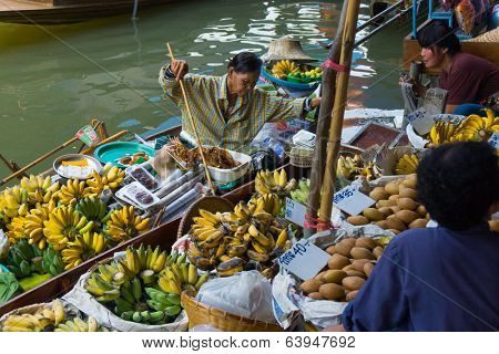 RATCHABURI, THAILAND - MARCH 24: Local peoples sell fruits, food and souvenirs at famous tourist attraction Damnoen Saduak floating market on March 24, 2014 in Ratchaburi, Thailand.