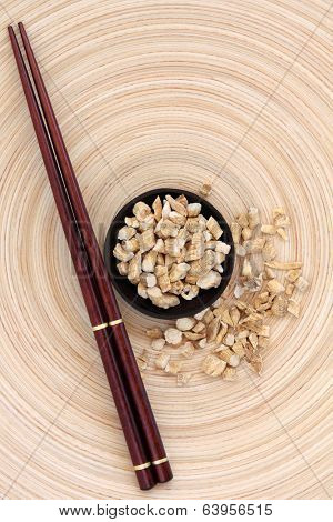 Ginseng root herb with chopsticks on a circular wooden bowl. Ren shen.