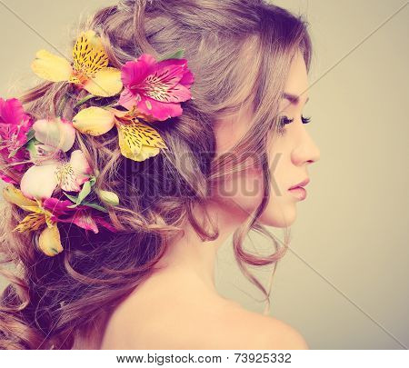 Beautiful girl, isolated on a light - grey background with varicoloured flowers in hairs, emotions, cosmetics