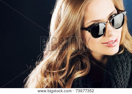 Close-up portrait of a smiling young lady with beautiful hair wearing black sunglasss.