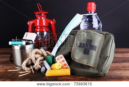 Emergency preparation equipment on wooden table, on dark background