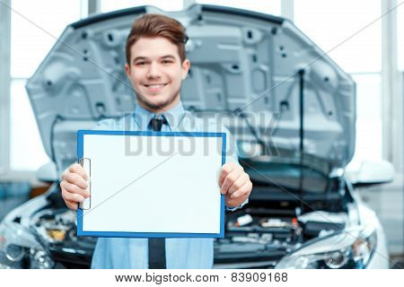Car service manager posing with a clipboard