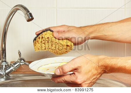 Hands with dirty dishes over the sink in kitchen
