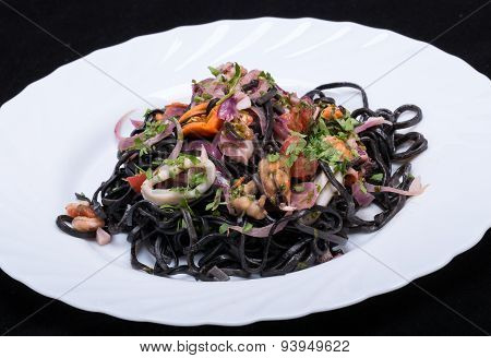 Black spaghetti with seafood and vegetables on plate