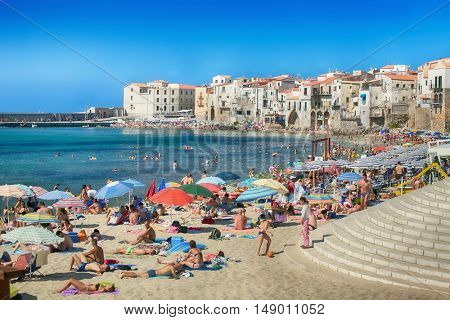 CEFALU,SICILY - JULY. 27. 2016: Unidentified people on sandy beach in Cefalu, Sicily, Italy at Sep 16, 2014. Cefalu is an attractive historic town and seaside resort.