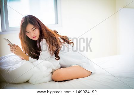 Girl Using A Mobile Phone Lying On The Bed At Home