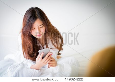 Girl Using A Mobile Phone Lying On The Bed At Home