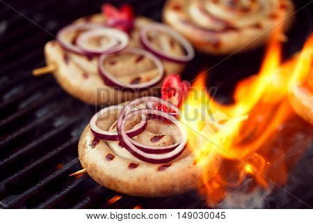 cumberland sausage, spiral pork sausage on bbq grill with flame, homemade