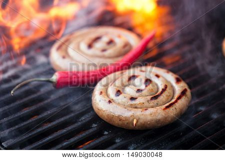 cumberland sausage, spiral pork sausage on bbq grill with flame, homemade