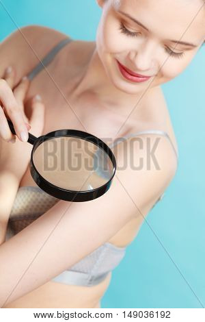 Woman Using Magnifying Glass To Examine Her Moles Skin