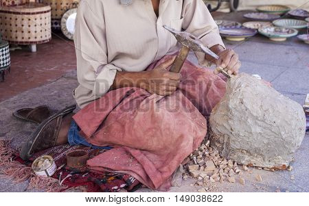 Artisan makes pieces for mosaic craftwork. He is shaping pieces from glazed tiles