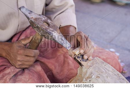 Artisan makes pieces for mosaic craftwork. He is shaping pieces from glazed tiles