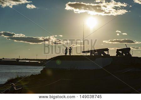 Fairhaven Massachusetts USA - September 24 2016: Members of Fairhaven Village Militia silhouetted by late afternoon sun while preparing for firing of cannon at Fort Phoenix in Fairhaven Massachusetts in a Revolutionary War reenactment