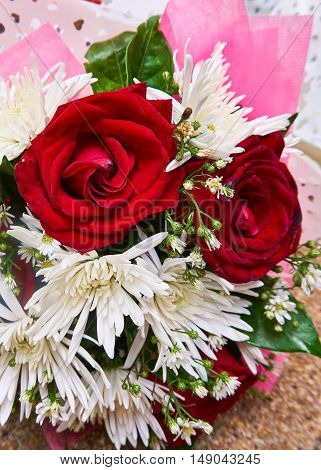 Red roses and white flowers in bouquet.
