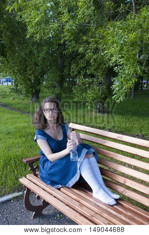 A girl resting in a park on a wooden bench