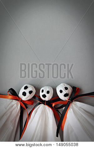 Halloween concept background : Three halloween ghosts DIY made from white tissue paper, black and orange ribbon on gray background