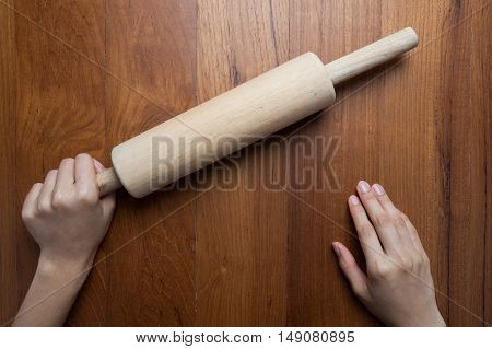 wooden rollerfemale cook rolling dough with rolling-pin. Closeup view