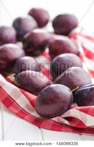 Fresh ripe plums on checkered napkin.