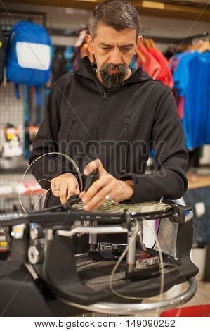 Tennis Stringer Holding Awl And Doing Racket Stringing
