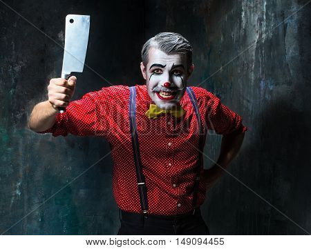 The scary clown holding a knife on dack. Halloween concept of horror and murderer
