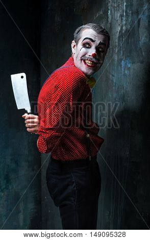 The scary clown holding a knife on dack. Halloween concept of horror and murderer
