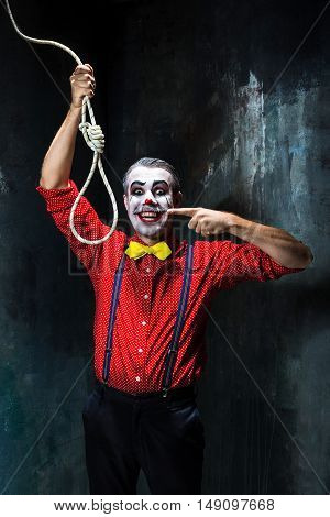 The scary clown and rope for hanging on dack. Halloween concept of horror and murderer
