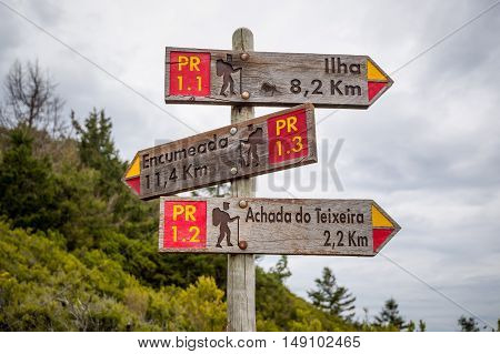 Wooden road sigh in the mountains of Madeira island with directions to popular hiking paths.