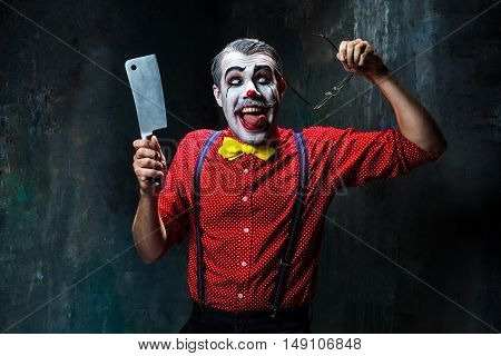 The crazy clown holding a knife on dack. Halloween concept of horror and murderer