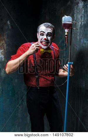 The scary clown and drip with blood on dack. Halloween concept of horror and murderer