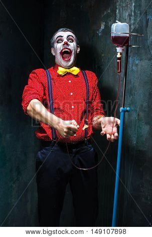 The scary clown and drip with blood on dack. Halloween concept of horror and murderer