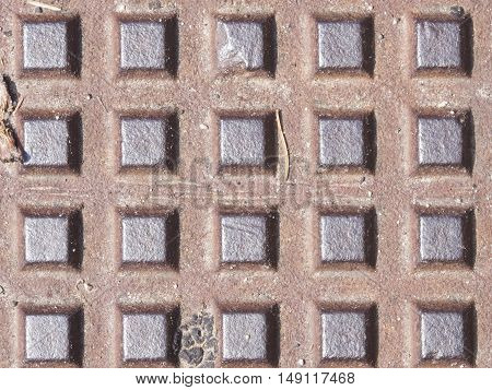 Old dark metal manhole texture with square pattern background macro selective focus.