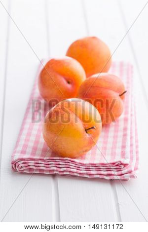 Fresh yellow plums on white table.