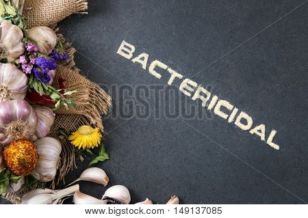 Composition of fresh garlic on a stone countertop with the inscription 