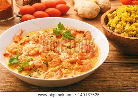 Indian cuisine - shrimps in ginger sauce and rice with curry and green pea.