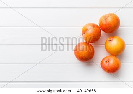 Fresh yellow plums on white table. Top view.