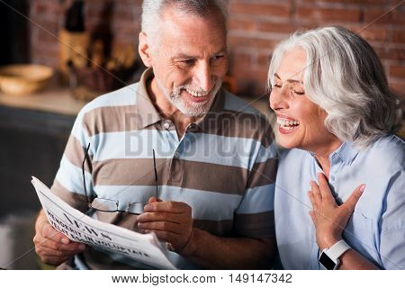 Funny. Attractive old couple having fun while reading morning newspaper