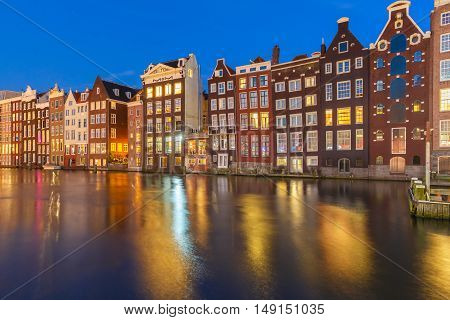 Beautiful typical Dutch dancing houses at the Amsterdam canal Damrak at night, Holland, Netherlands.