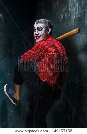 The scary clown and baseball-bat on dack. Halloween concept of horror and murderer