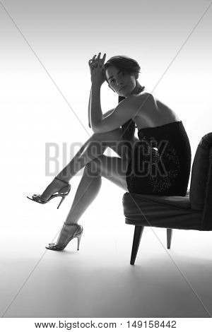 Beautiful sitting woman instudio with high heel shoes, white background
