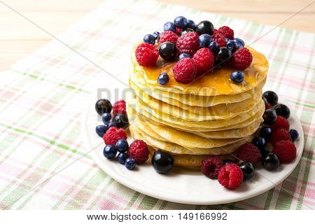Stack of pancakes with honey blueberry raspberry and blackcurrant. Stack of homemade breakfast pancakes served with fresh berries.