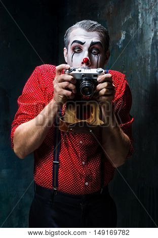 The scary clown and a camera on dack. Halloween concept of horror and murderer