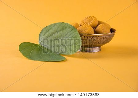 indian festival dussehra or vijayadashmi or ayudh puja, showing apta leaf or Bauhinia racemosa with traditional indian sweets pedha in silver bowl
