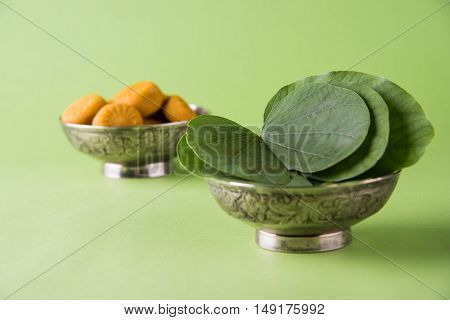 indian festival dussehra or vijayadashmi or ayudh puja, showing apta leaf or Bauhinia racemosa with traditional indian sweets pedha in silver bowl