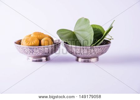 indian festival dussehra or vijayadashmi or ayudh puja, showing apta leaf or Bauhinia racemosa with traditional indian sweets pedha in silver bowl