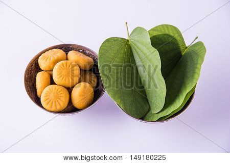 indian festival dussehra or vijayadashmi or ayudh puja, showing apta leaf or Bauhinia racemosa with traditional indian sweets pedha in silver bowl