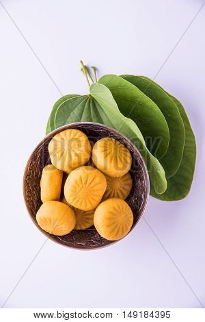 indian festival dussehra or vijayadashmi or ayudh puja, showing apta leaf or Bauhinia racemosa with traditional indian sweets pedha in silver bowl