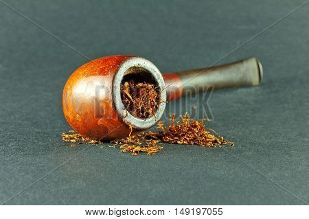 Tobacco pipe with tobaco isolated on gray background.
