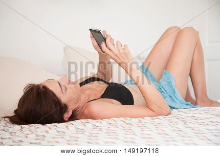 Woman Lying On The Bed Face Up Touching Smartphone Screen